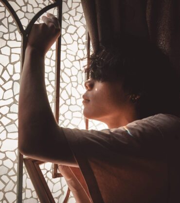 Man reflecting by a window representing men's mental health care in Miami