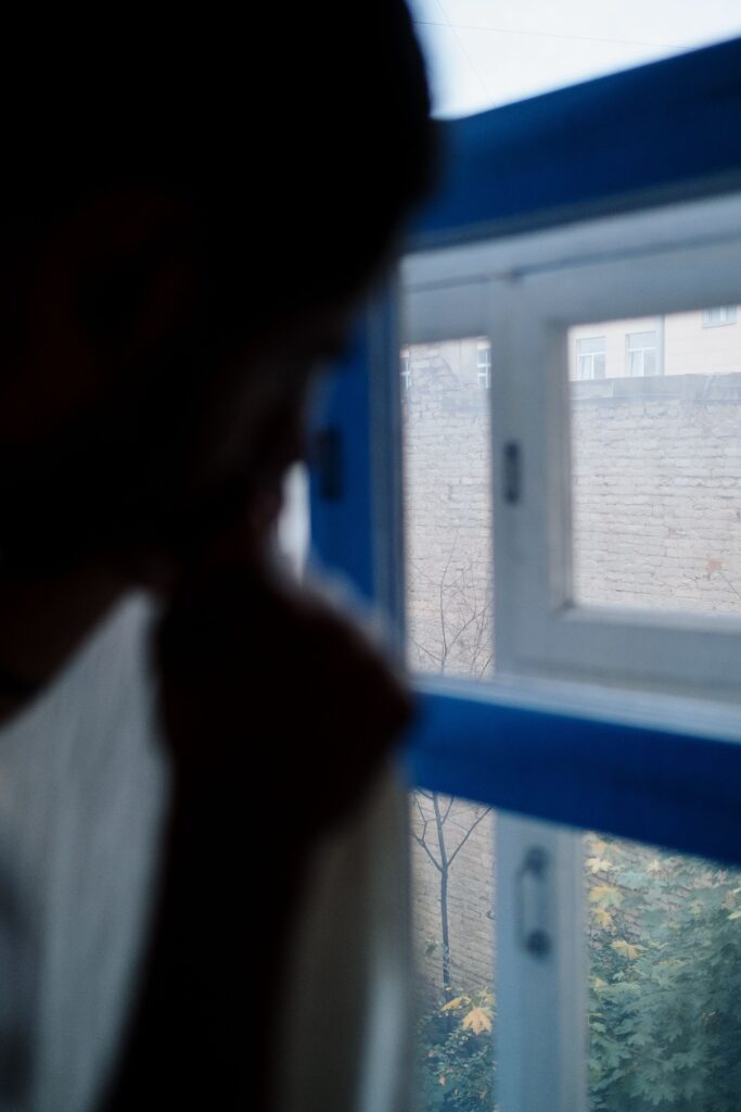 Person by a window in low light representing seasonal affective disorder in Miami