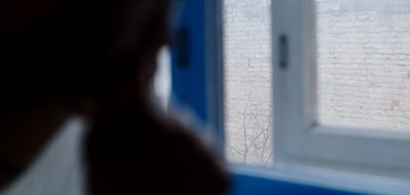 Person by a window in low light representing seasonal affective disorder in Miami