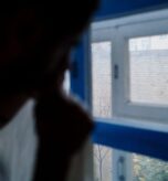 Person by a window in low light representing seasonal affective disorder in Miami