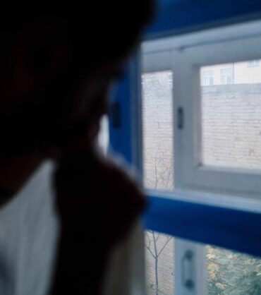 Person by a window in low light representing seasonal affective disorder in Miami